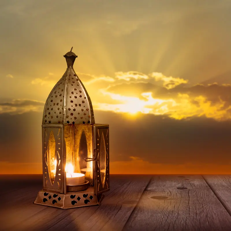 اليوم 20 من شهر رمضان - دعاء، عبارات و تهنئة مع صور, فانوس تقليدي يتوهج بدفء على خلفية غروب الشمس الجذابة.